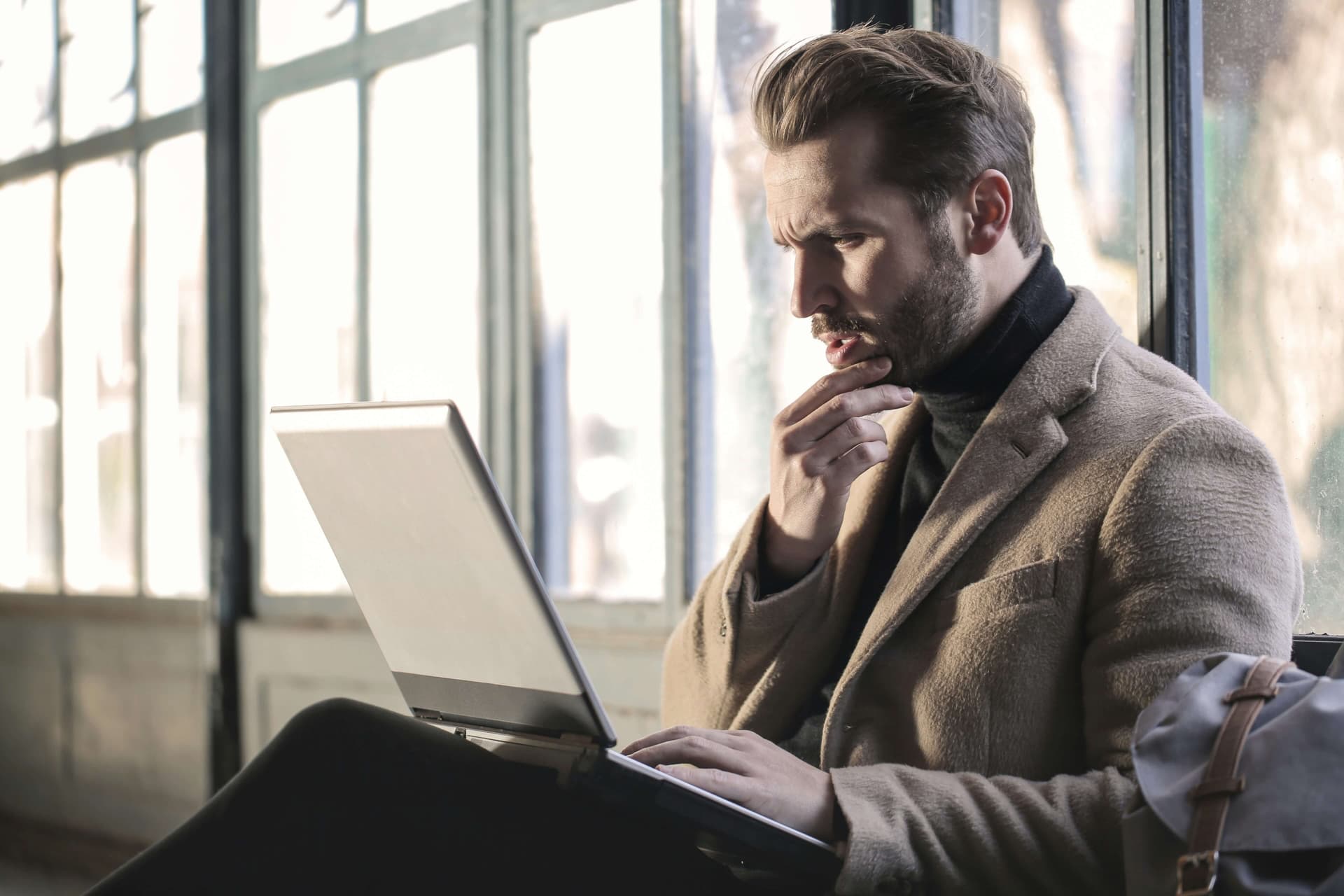 Man die nadenkt en financiële beslissingen neemt terwijl hij naar laptop kijkt